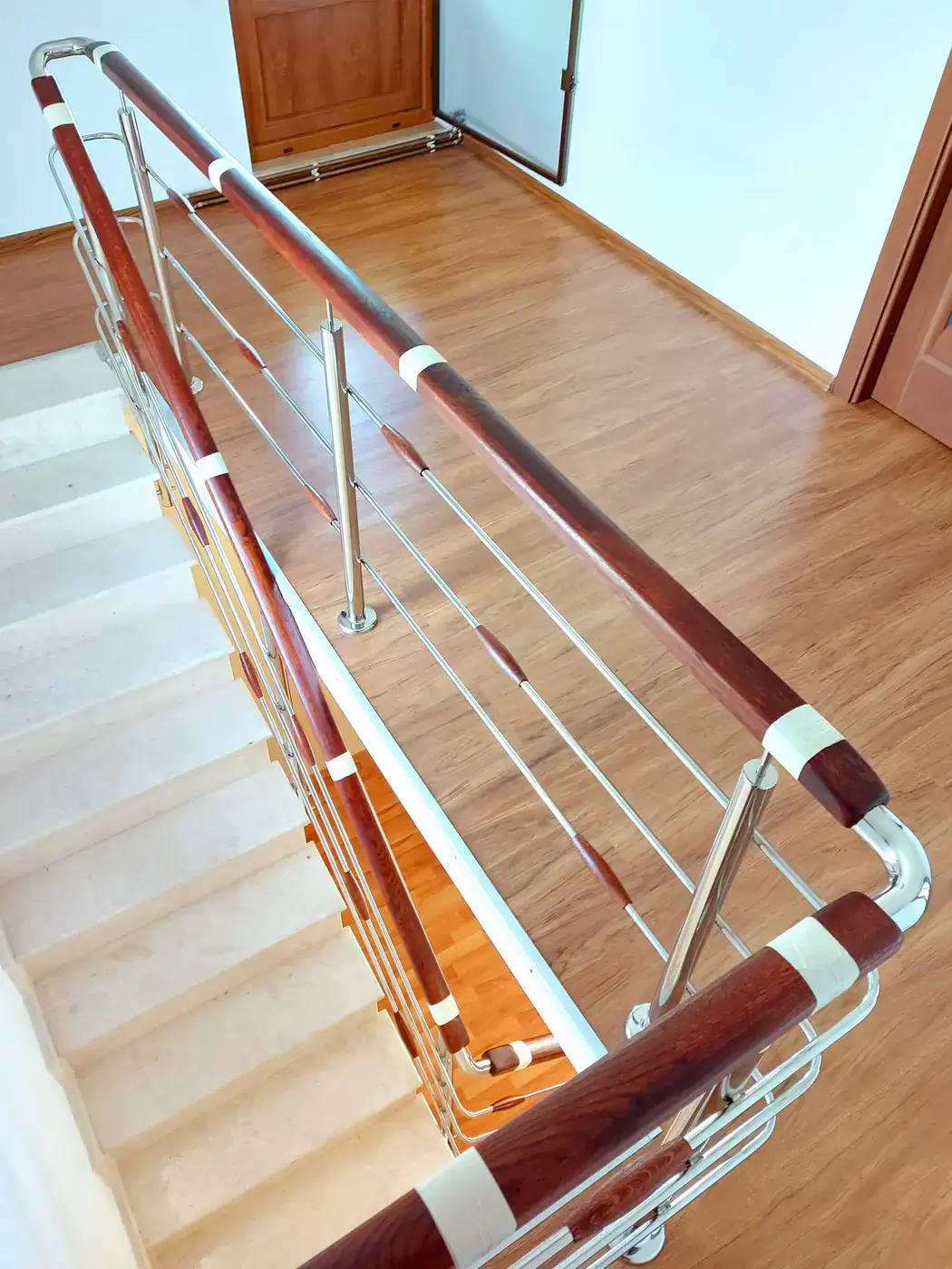 Detaliu real de scară cu balustradă din inox și mână curentă din lemn