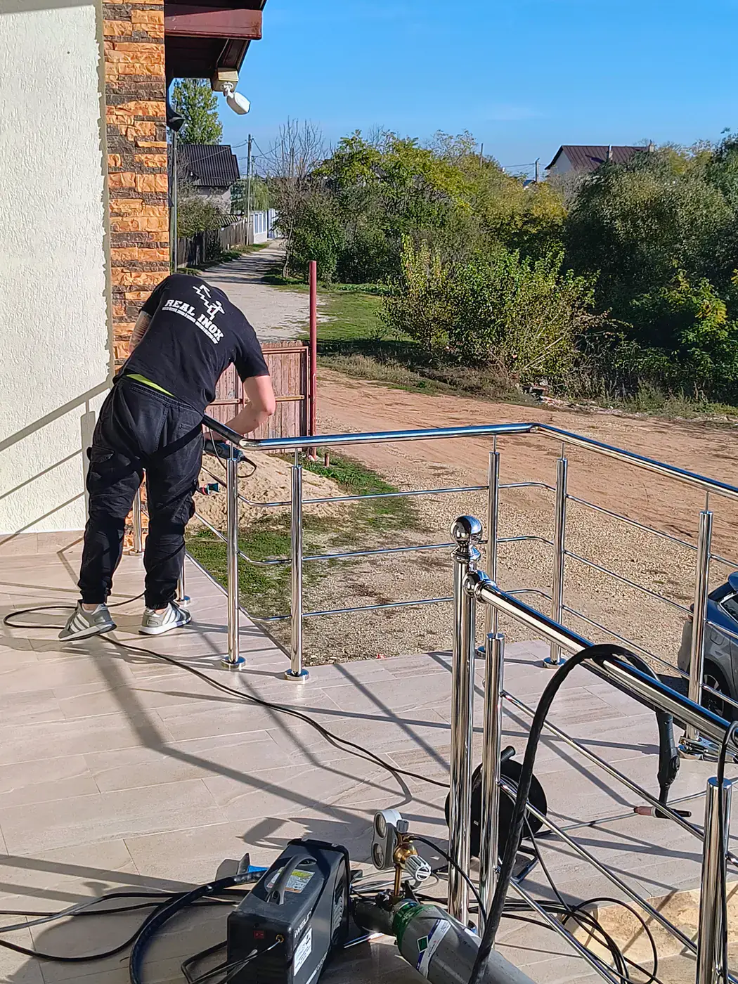 Executant Real Inox lucrând la detaliile unei balustrade exterioare